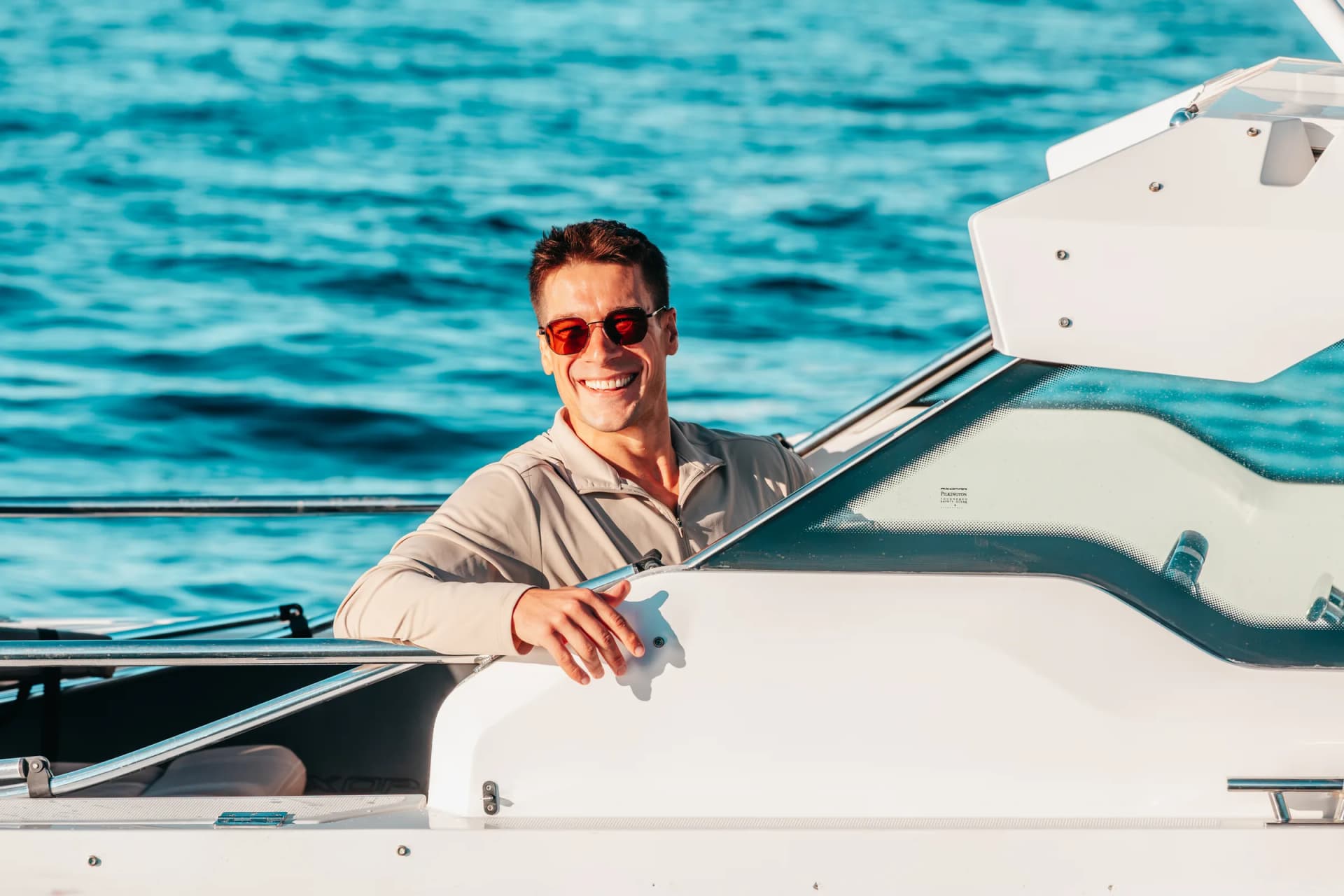 Captain Jeremy standing at the side deck of Sea La Vie, one hand on the coaming, deep blue bay water behind him