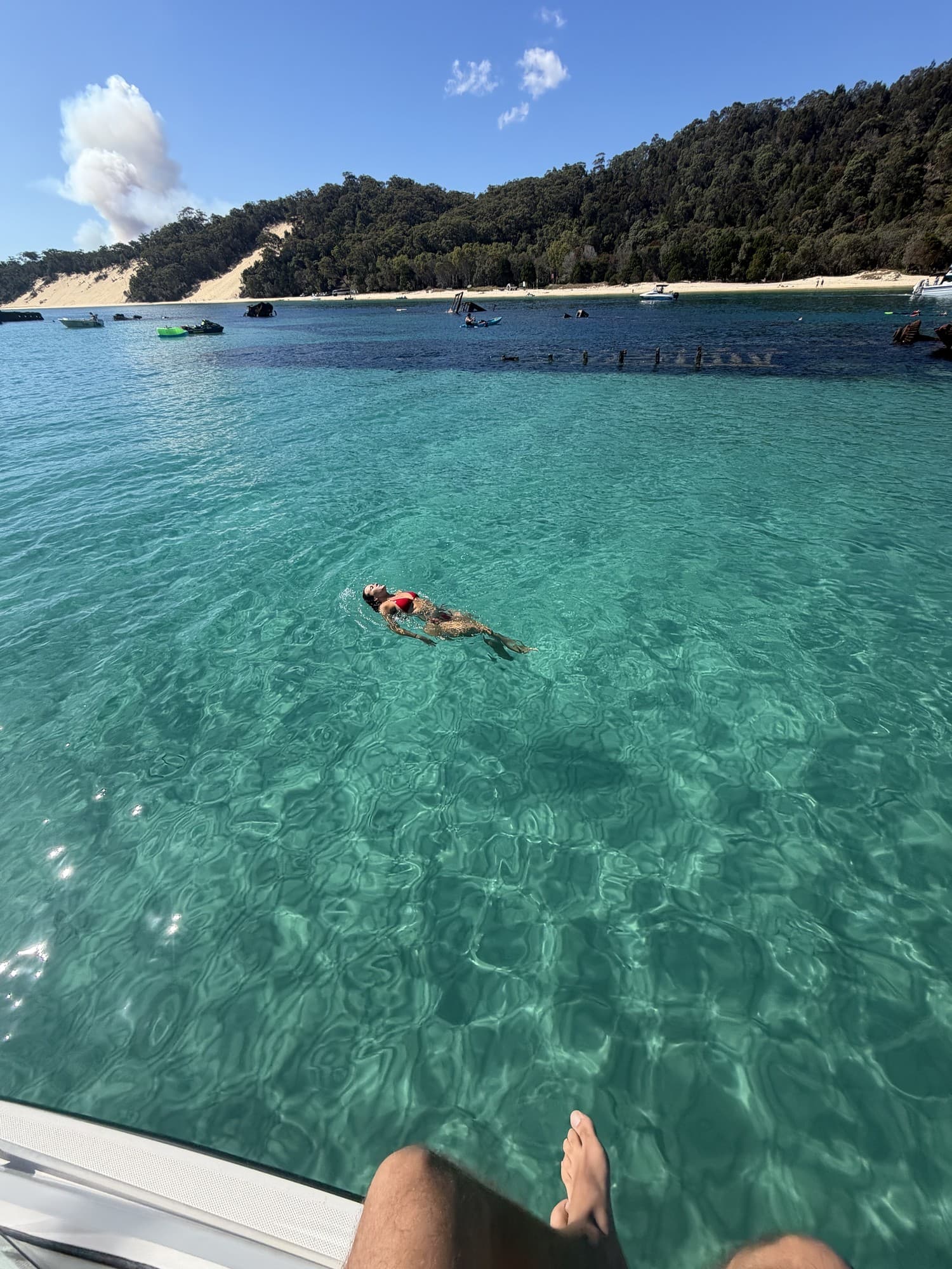 Guest floating on her back in clear aqua water beside the Tangalooma Wrecks